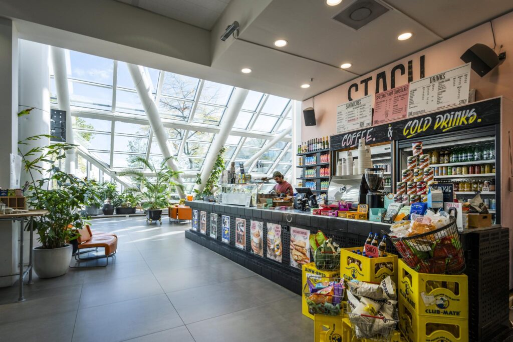 Moderne koffiebar STACH aan de Johan Huizingalaan met veel daglicht, planten en een breed assortiment aan snacks en drankjes.